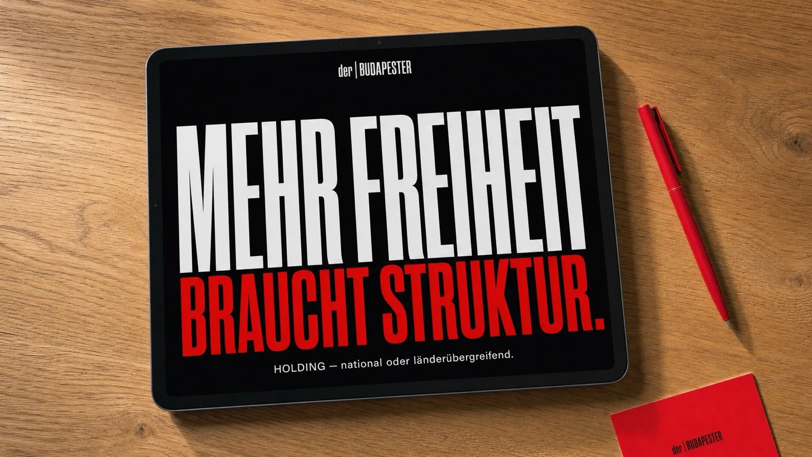Tablet auf Holztisch mit der Aufschrift Mehr Freiheit braucht Struktur und rotem Stift