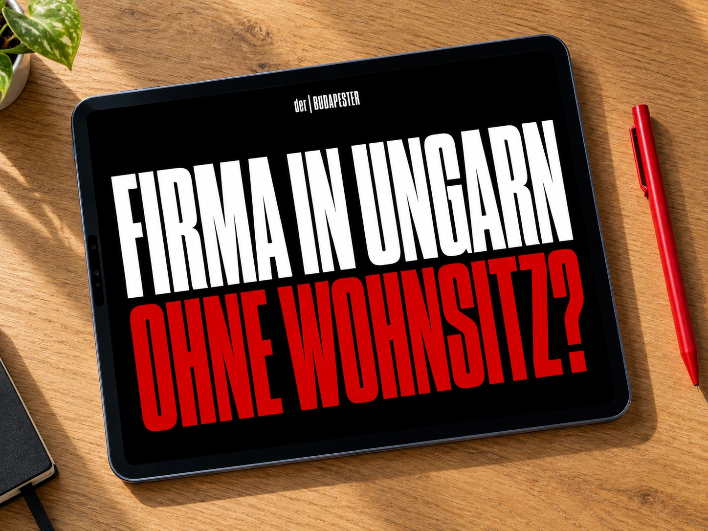 Tablet in Draufsicht auf einer Holzoberfläche neben einem roten Stift. Auf dem Display stehen der | BUDAPESTER, FIRMA IN UNGARN und OHNE WOHNSITZ?.
