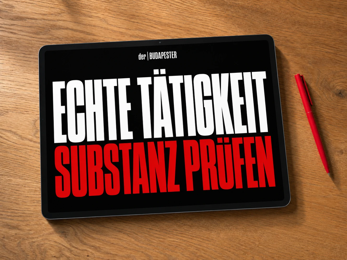 Draufsicht auf ein schwarzes Tablet auf einem Holztisch neben einem roten Stift. Auf dem Display stehen der | BUDAPESTER, ECHTE TÄTIGKEIT in Weiß und SUBSTANZ PRÜFEN in Rot.